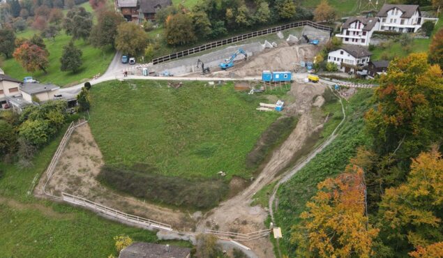 Baustelle auf grünem Hügel mit umliegenden Häusern