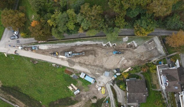 Baustelle mit Baggern und umliegenden Häusern aus der Luft