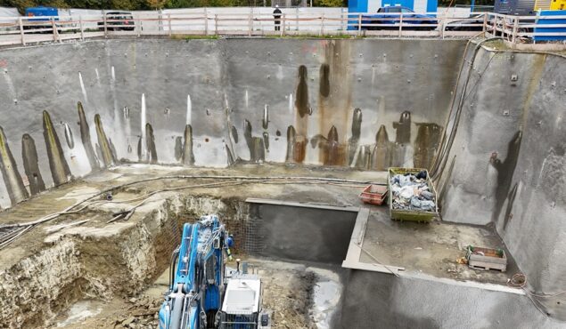 Baugrube mit Bagger und Betonwänden auf Baustelle